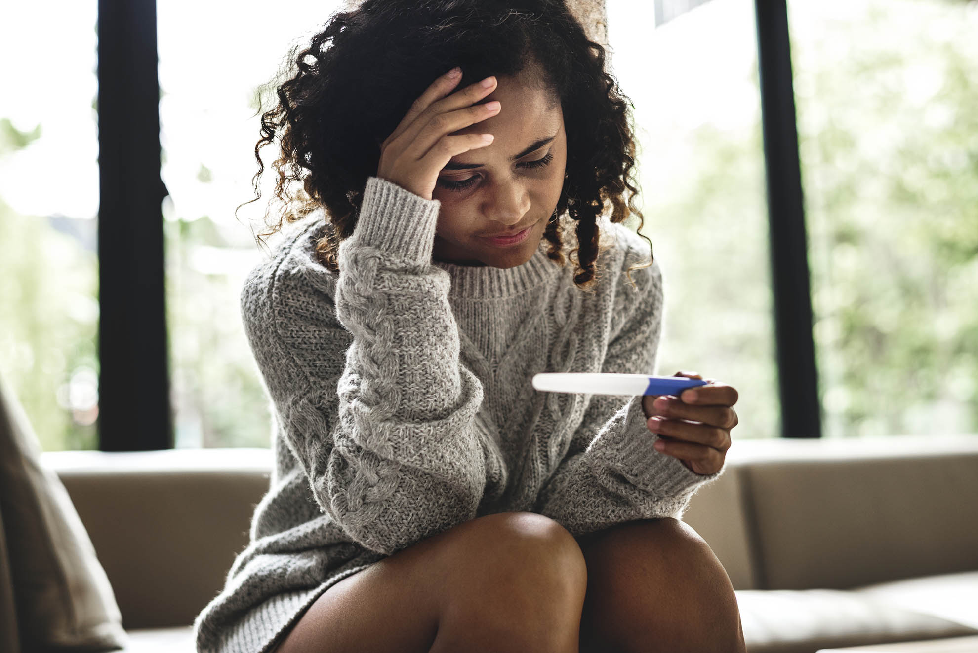 upset woman looking at a pregnancy test
